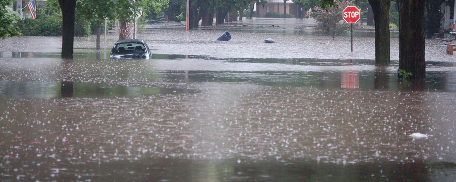 Flooding in the Midwest A flooded street with a half-submerged car and a stop sign