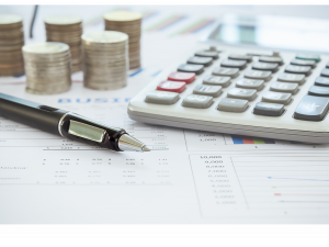 Close up of a calculator, pen, and stacks of quarters