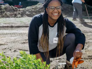 laughing woman kneeling next to plant
