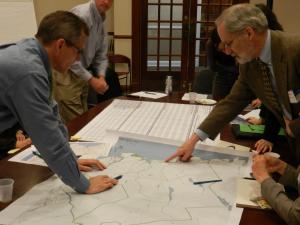 group of people pointing to a map on a table