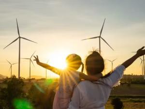 A woman and child looking at a field of windmills at sunset