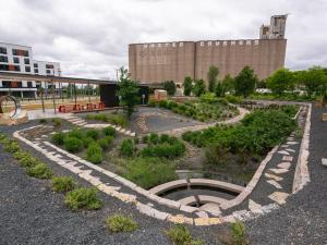 Uniquely designed rain garden featuerd in the foreground with a large brown industrial tower rising in the background
