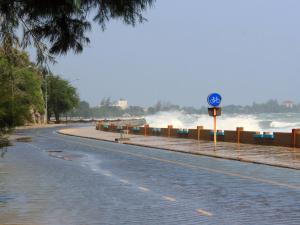 Giant storm waves splash above sea wall and the road is beginning to flood. 