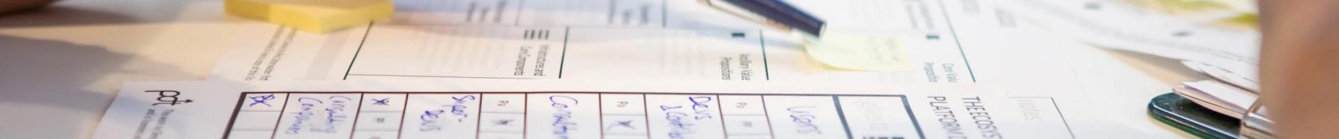 Someone holding a blue marker and pointing at the papers beneath them