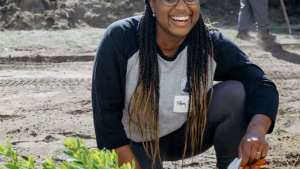 laughing woman kneeling next to plant