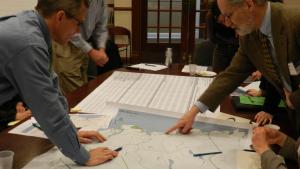 group of people pointing to a map on a table