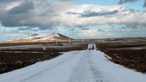 Icy road leading into a small town with snoq capped mountains and three windmills in the background