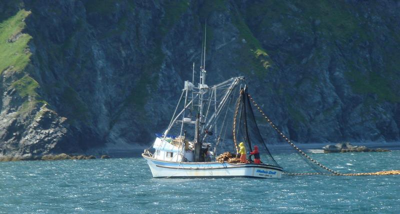 Fishing boat on water in front of cliffs