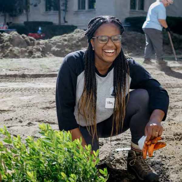 laughing woman kneeling next to plant