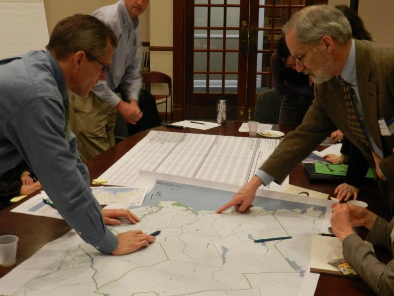group of people pointing to a map on a table