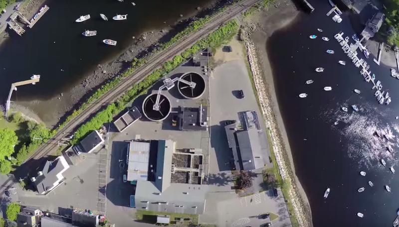 Aerial view of water tanks and buildings surrounded by water with recreational boats.