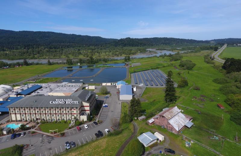 Casino, solar array, river, and mountains under a blue sky