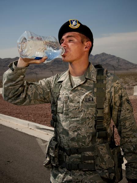 An airman drinks bottled water to stay hydrated