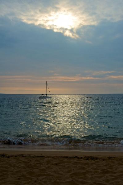 Sunlight, clouds, ocean (with a boat), and beach