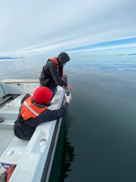 Two people at the edge of a boat on calm water