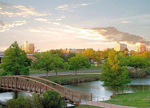 A pedestrian bridge over the Concho River, with downtown San Angelo, Texas in the background