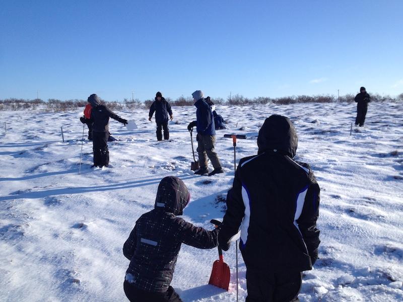 People on snowy surface with shovels and coring instruments
