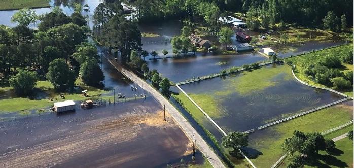 Flood waters from a river at the top of the image inundate fields and a farm.