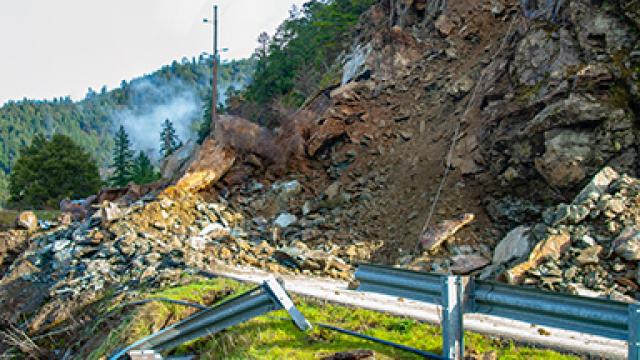 Photo of a road covered with rocks next to a hill