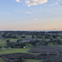 blue sky with clouds over a flat green landscape